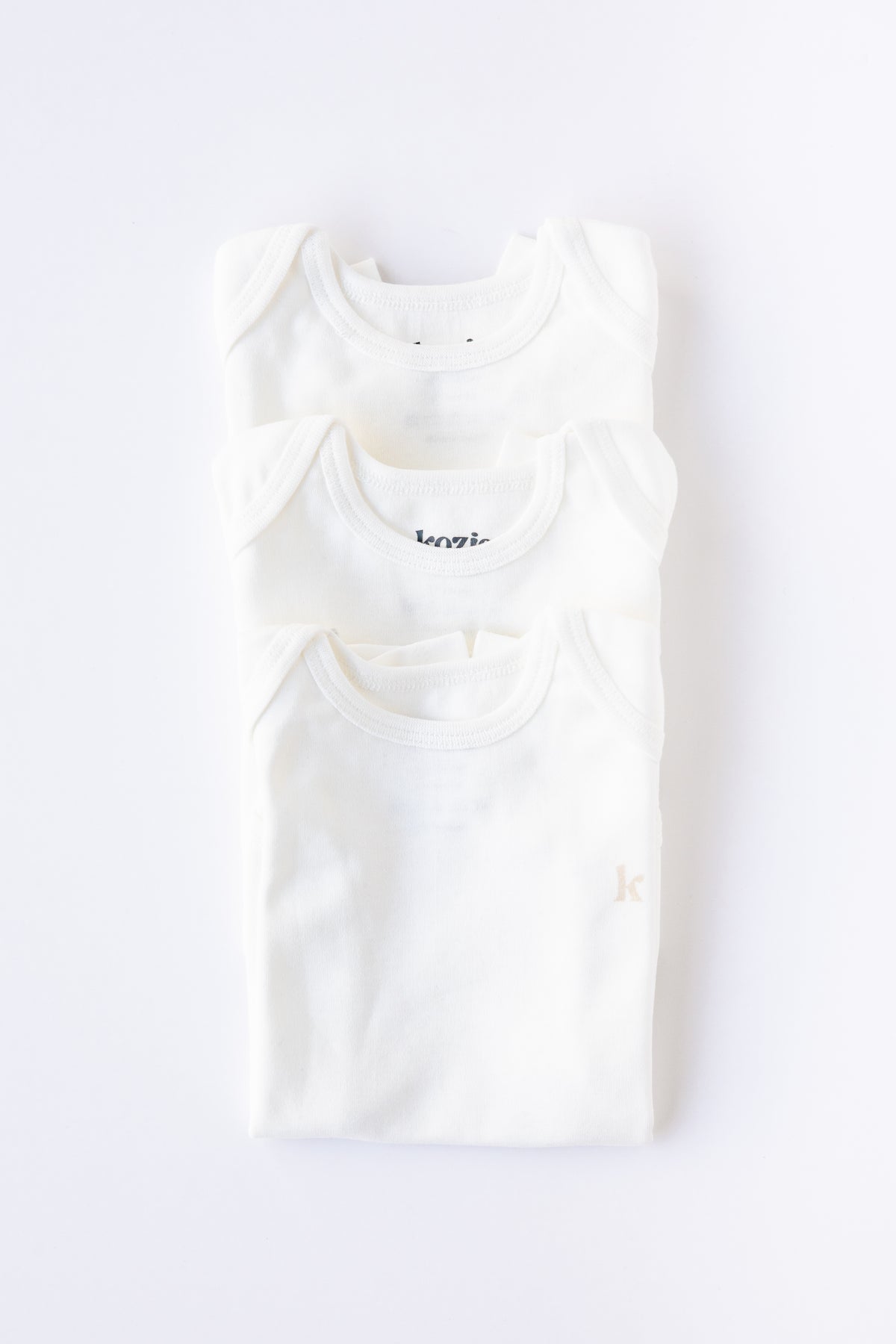 Three white short sleeve bodysuits folded and stacked