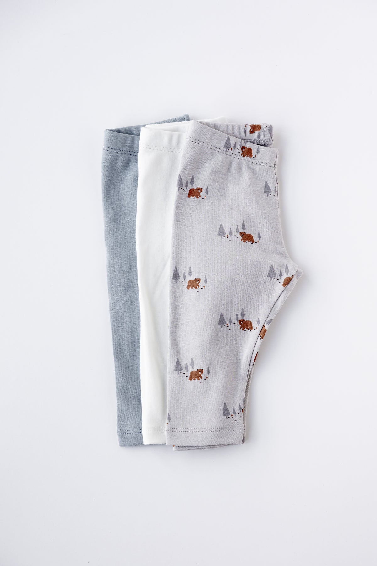 Three pairs of baby leggings in grey, white and Woodland print