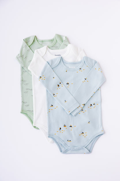 Three long sleeve bodysuits fanned out in sage, white and blue with boat print