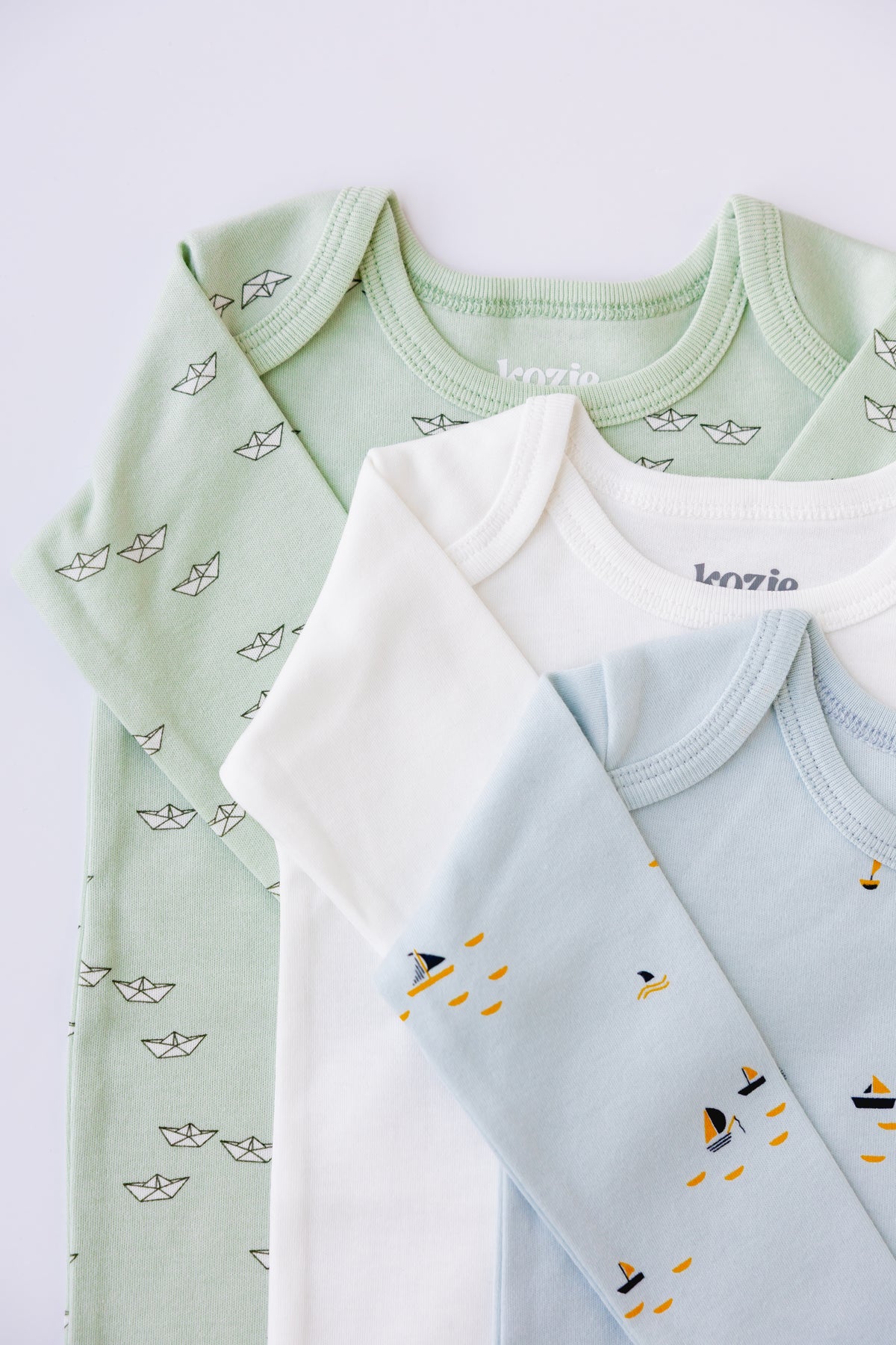 Sage, white and blue long sleeve bodysuits stacked, showing the boat print