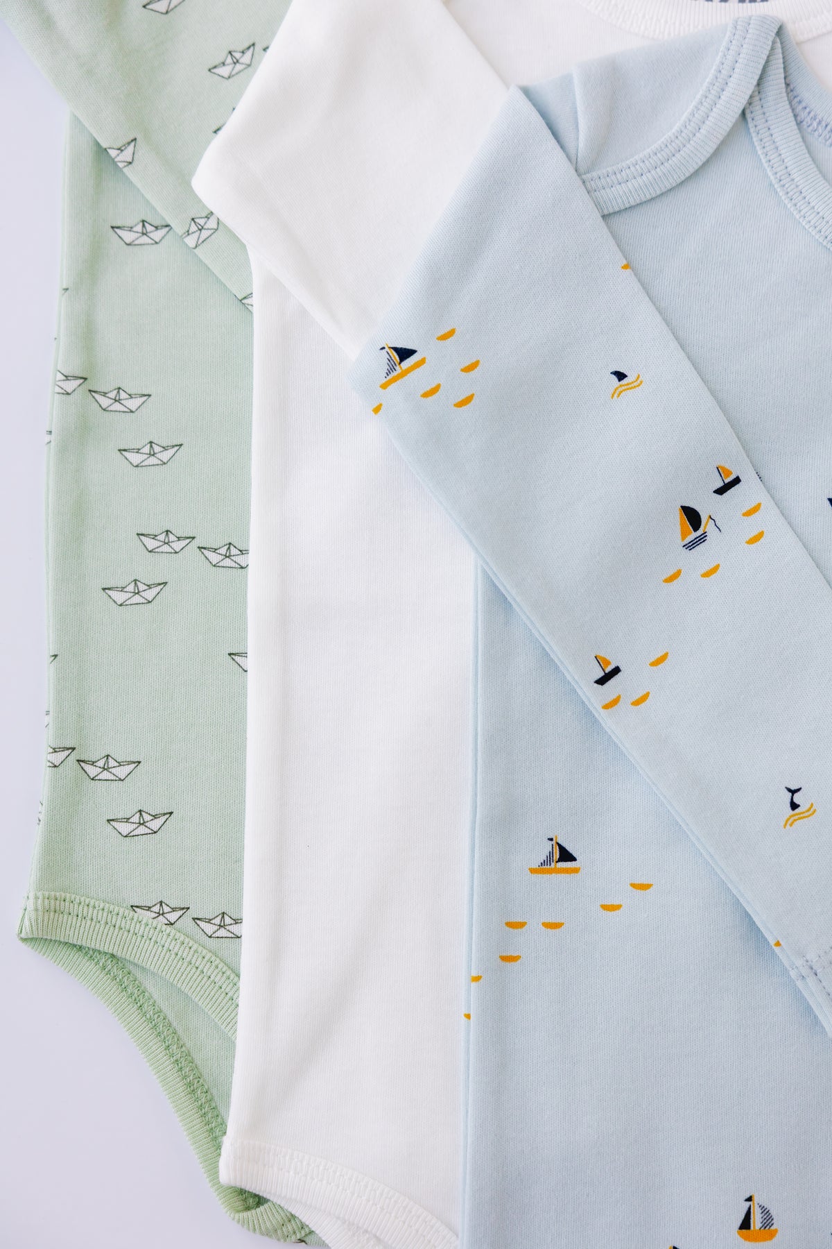 White and blue boat print long sleeve bodysuits laid flat