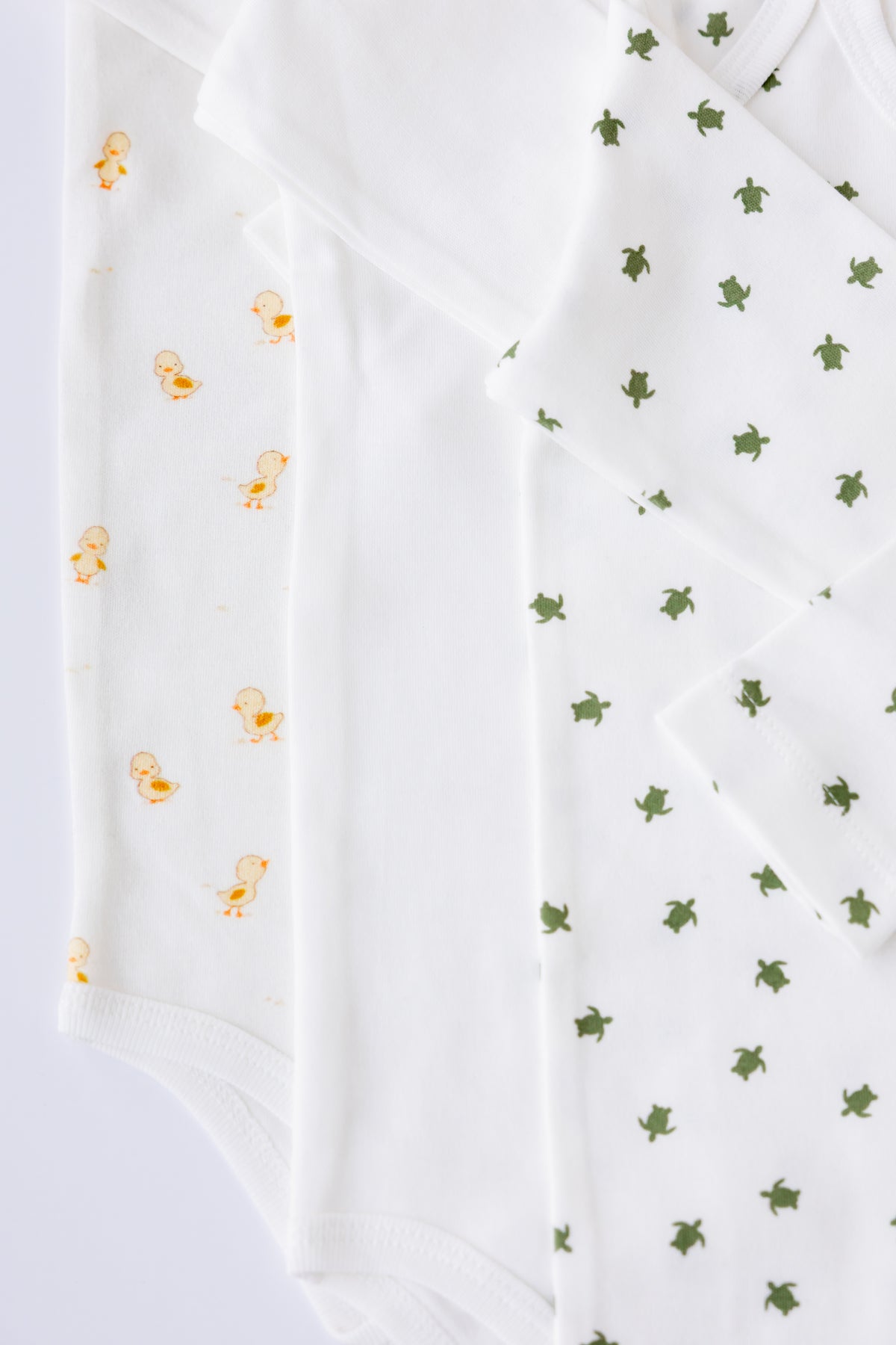 Two Tiny Explorer print long sleeve bodysuits, laid flat