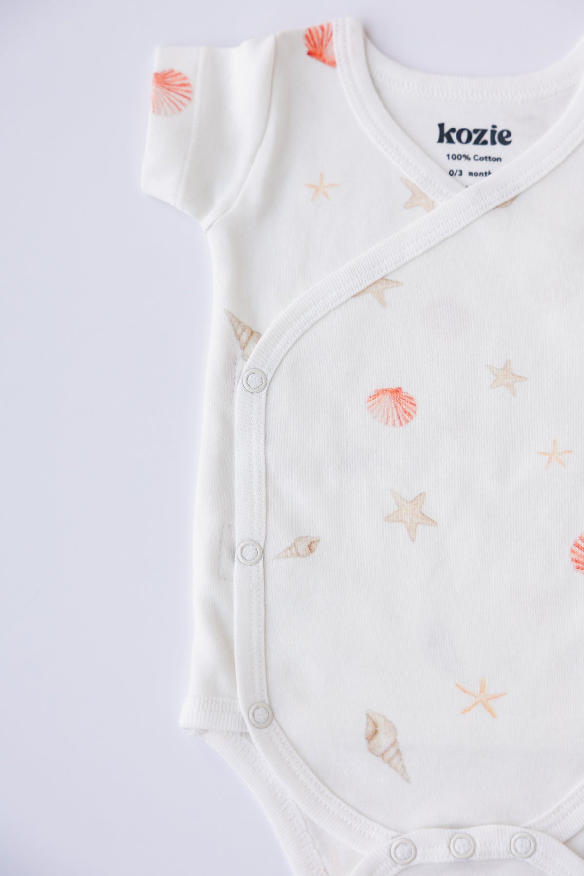 Close-up of the wrap front and Kozie label on a Coastal Day Dream kimono bodysuit