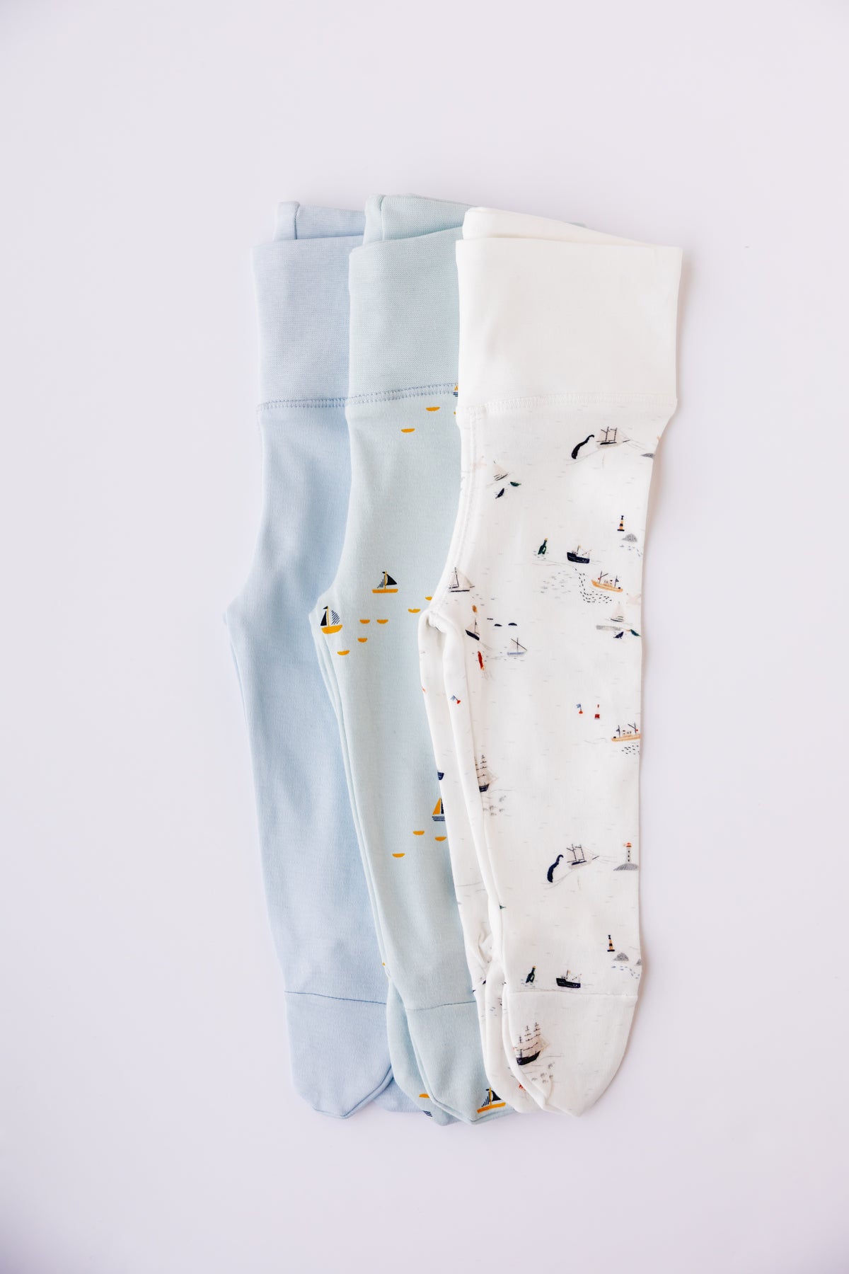 Three pairs of footed leggings in sky blue, white and Sailing Days print