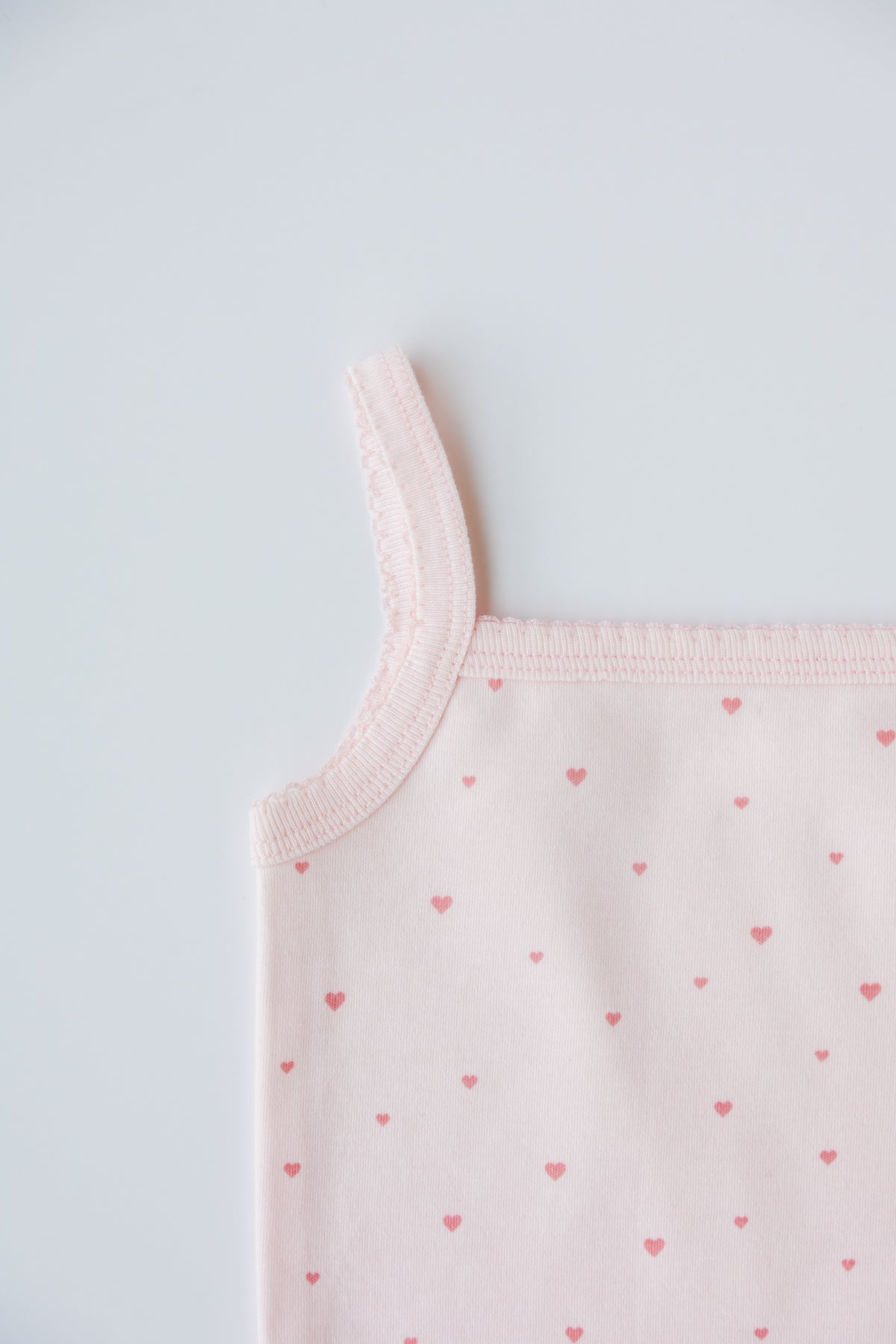 Blush Tiny Love print sleeveless bodysuit laid flat