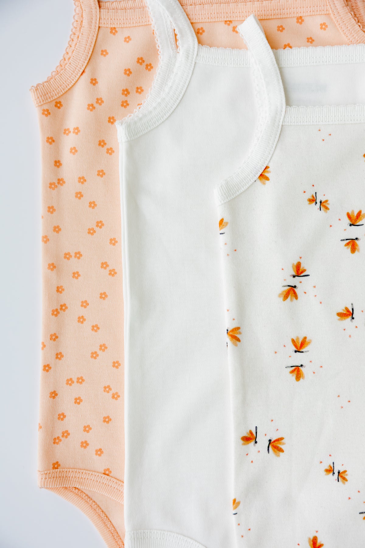 Two Daisy Dreams print sleeveless bodysuits, laid flat