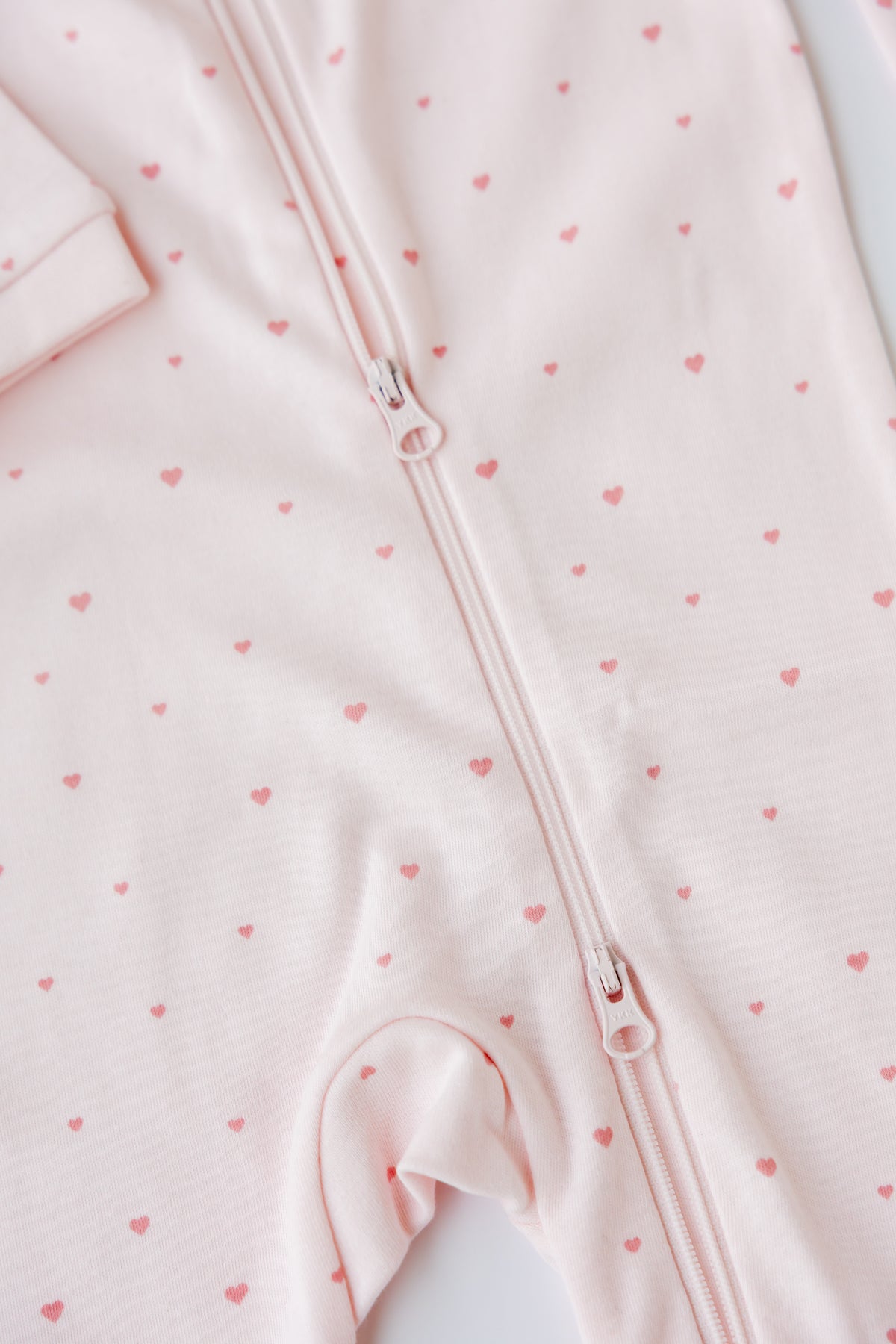 Close-up of the Tiny Love print and two-way zip on the blush sleepsuit