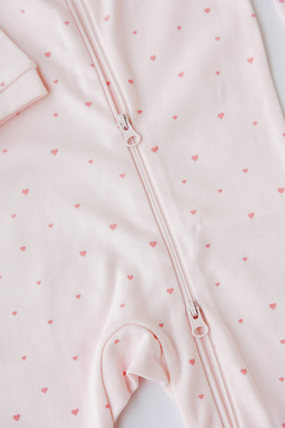 Close-up of the Tiny Love print and two-way zip on the blush sleepsuit