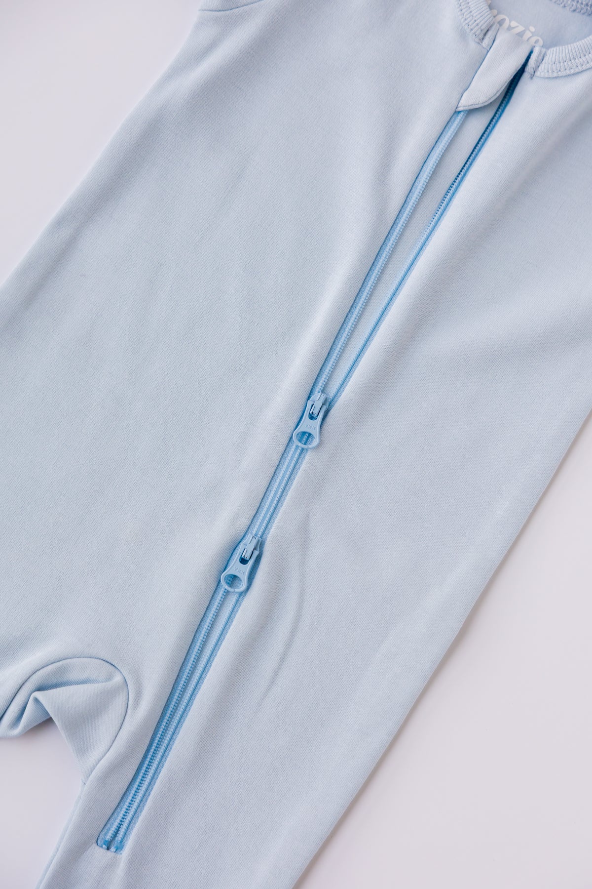 Close-up of the two-way zip on the sky blue footed sleepsuit
