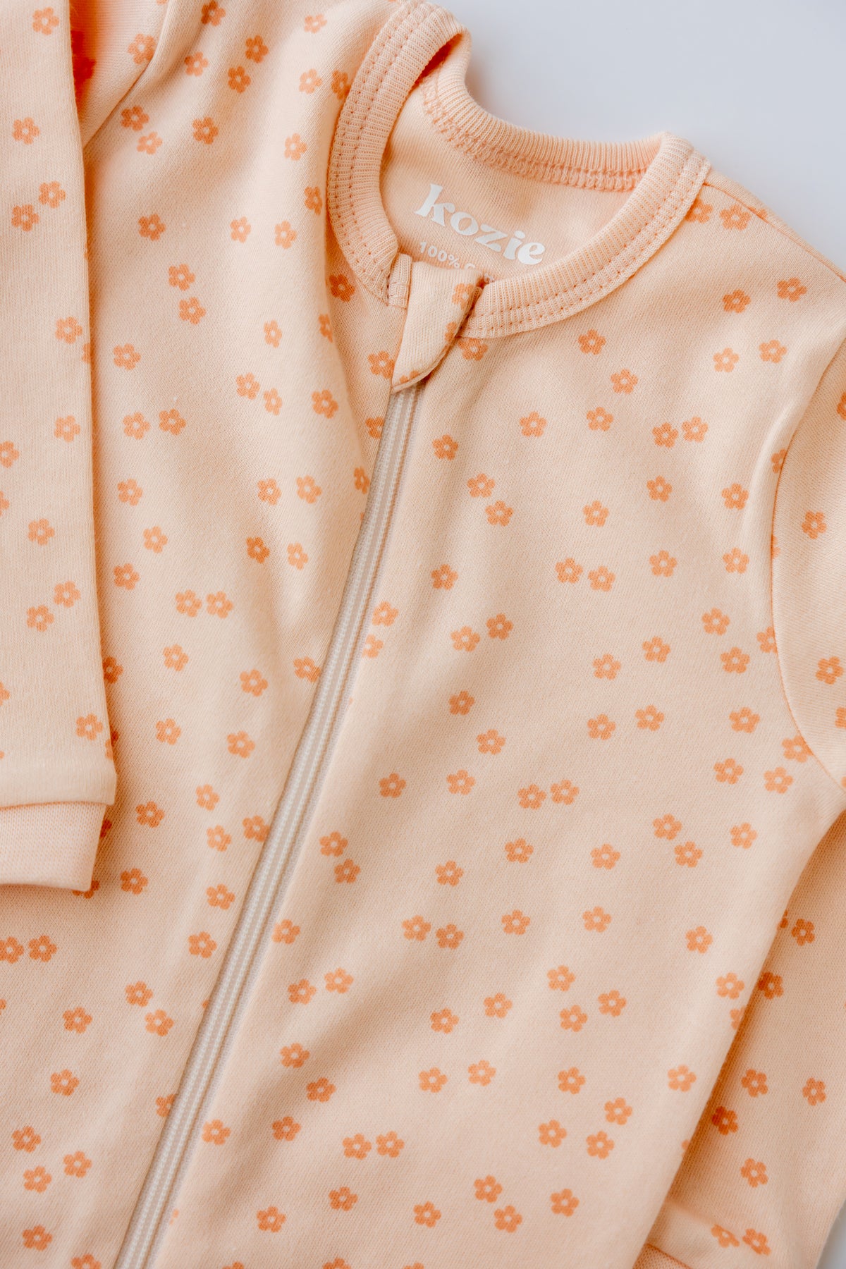 Close-up of the Daisies print and zip on the coral sleepsuit