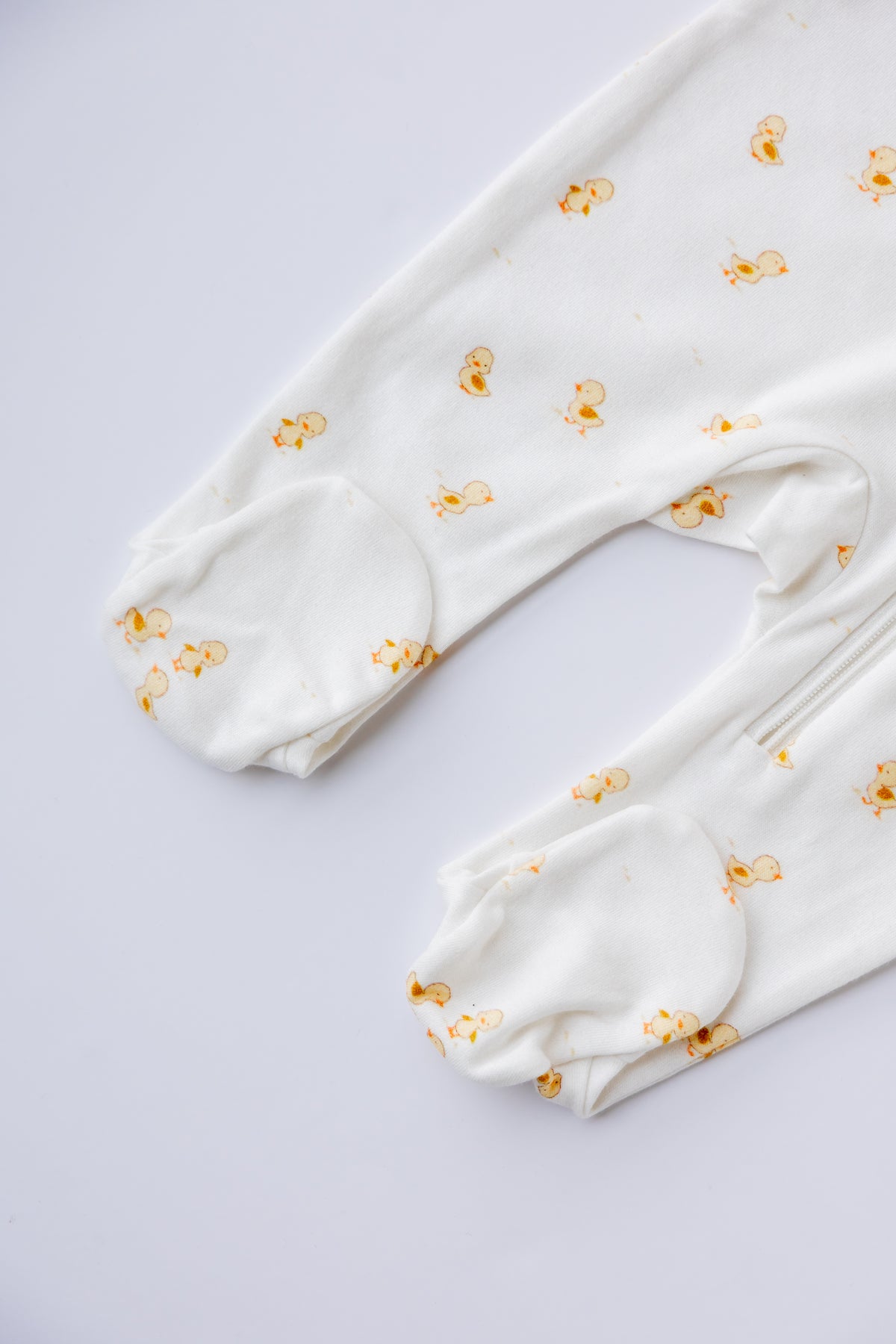 Close-up of the Ducky Days duck print on the white sleepsuit