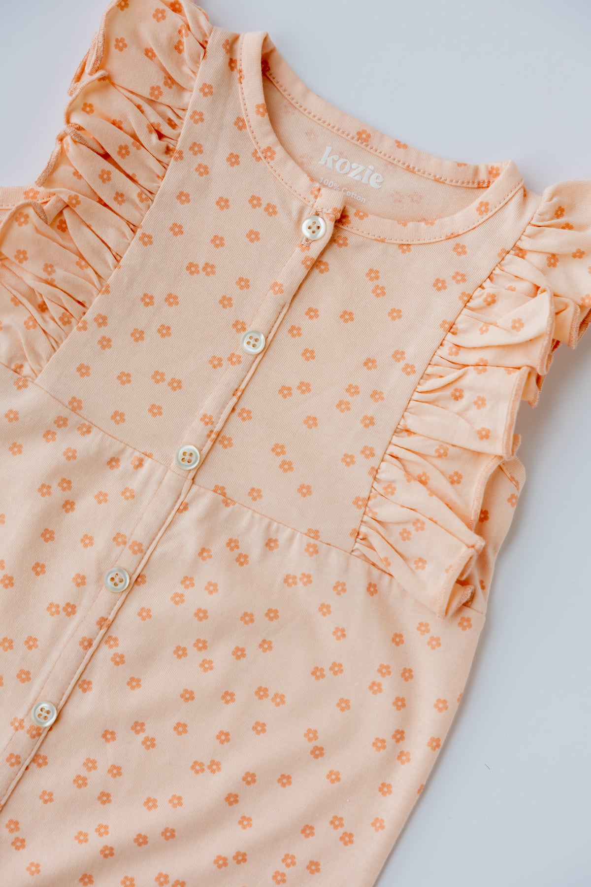Close-up of the ruffle detail on the coral Daisies romper