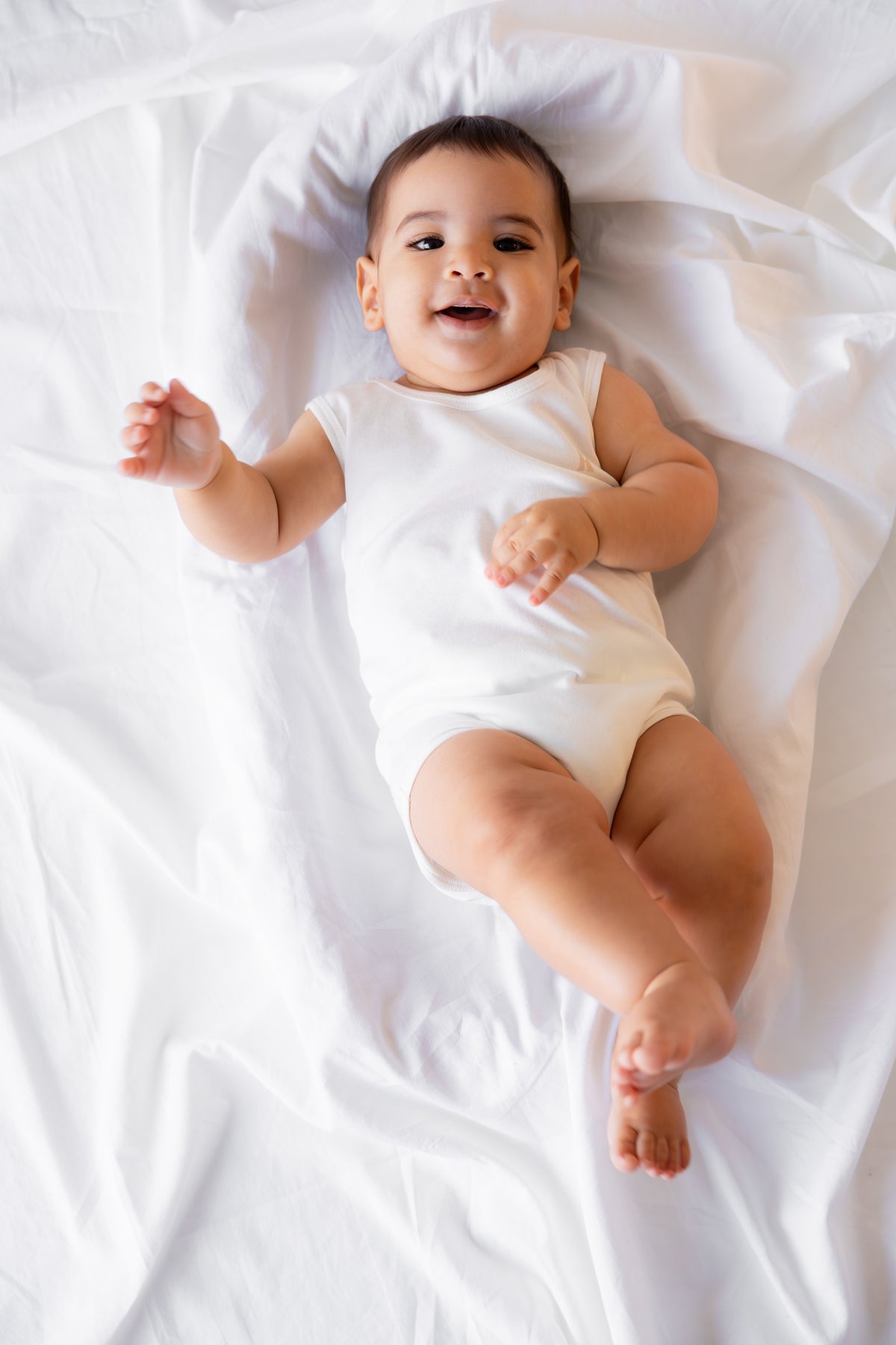 Baby lying down in a white sleeveless bodysuit