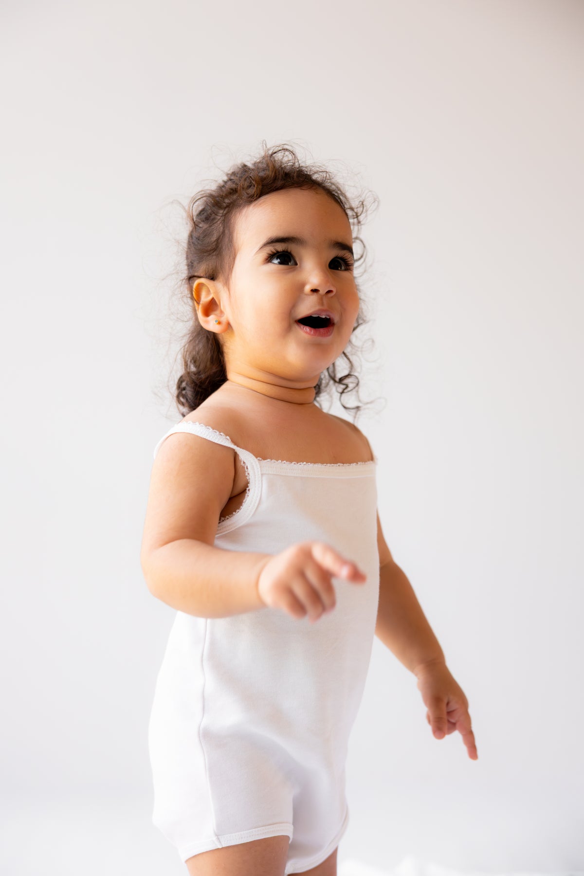 Toddler wearing a white sleeveless bodysuit with lace trim