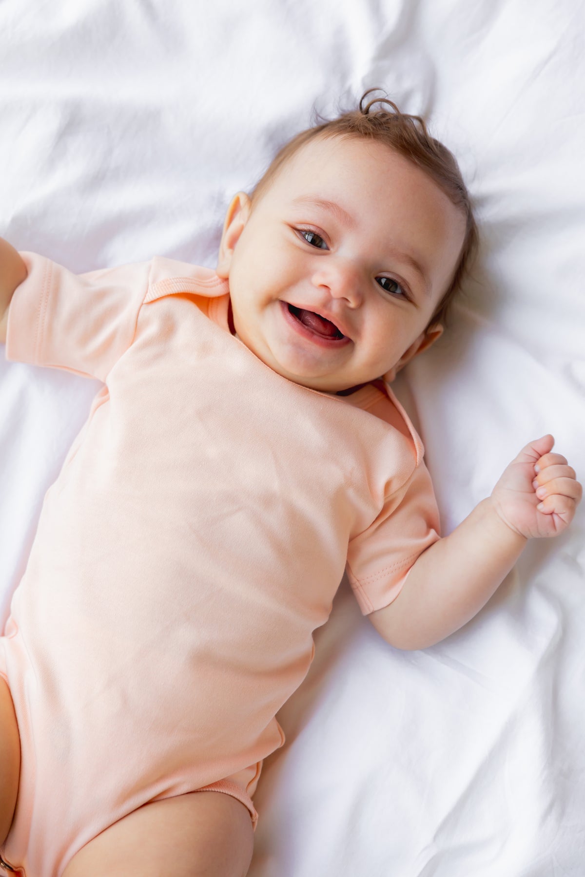 Baby lying down in a blush short sleeve bodysuit