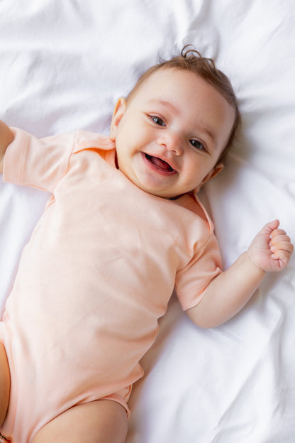 Baby lying down in a blush short sleeve bodysuit
