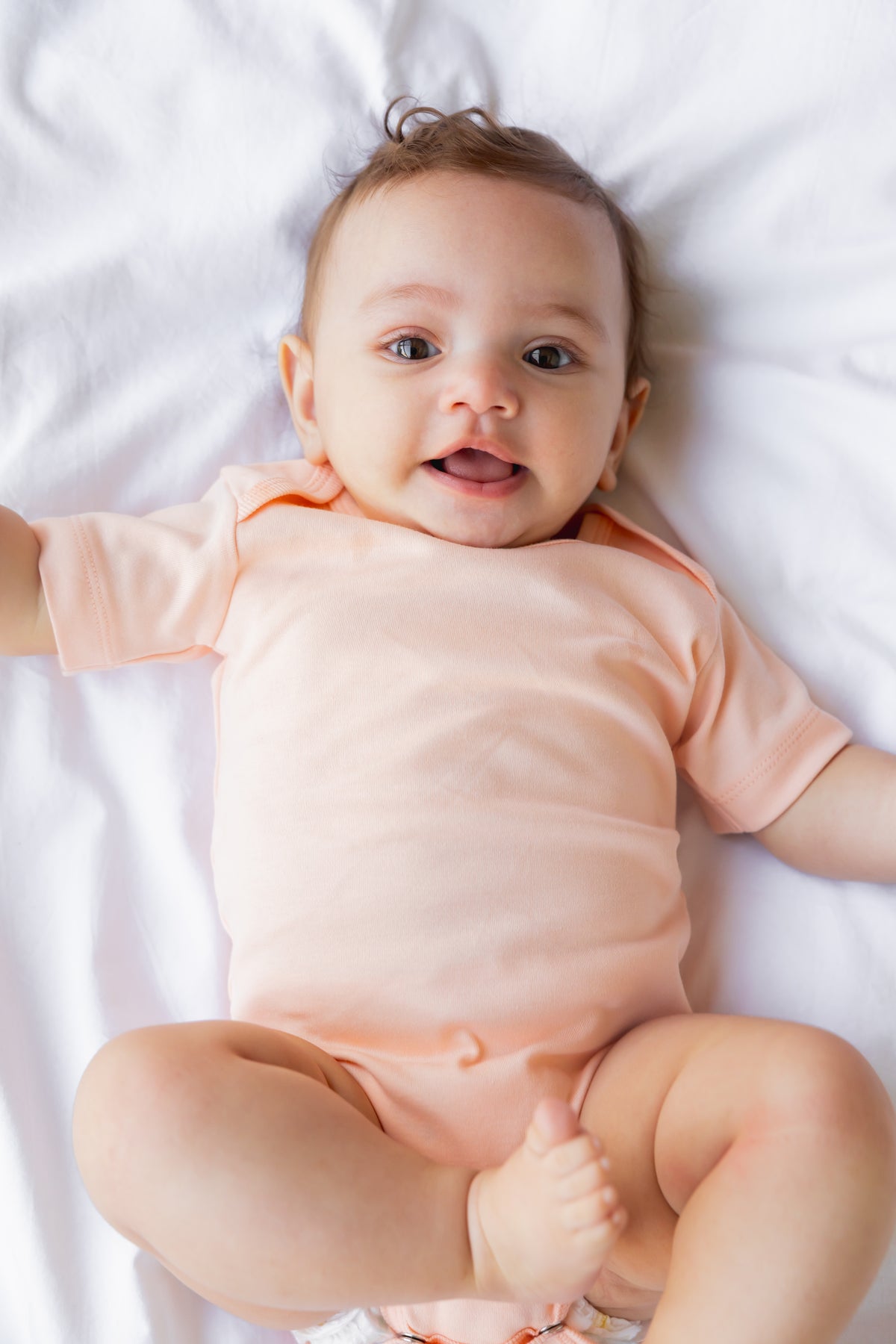 Baby lying down in a white Seashell print short sleeve bodysuit