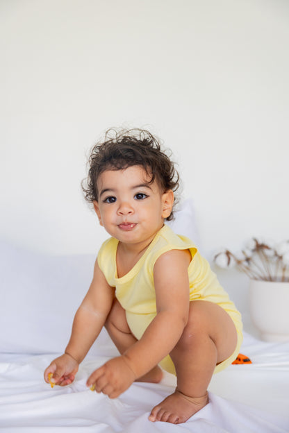 Toddler sitting in a Turtle Bay print sleeveless bodysuit