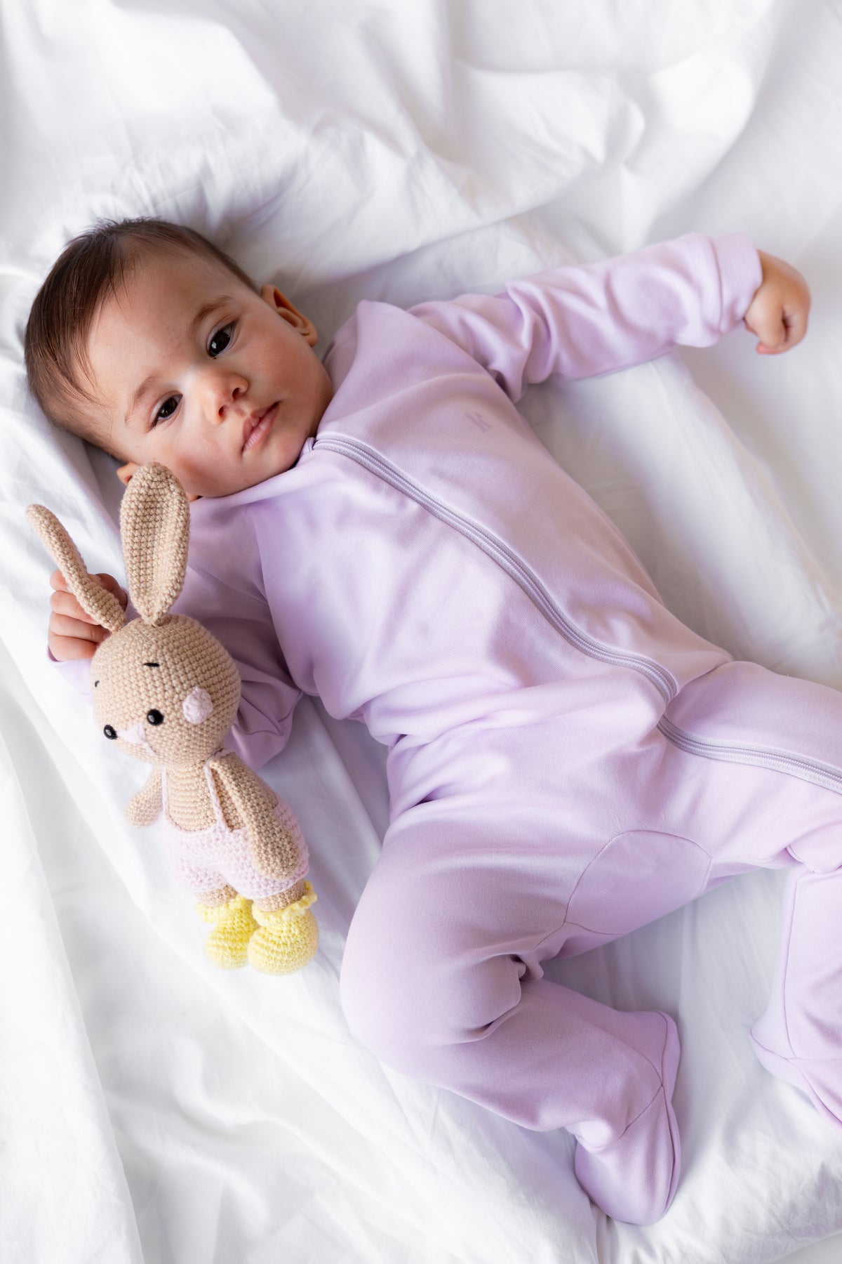 Baby lying down in the Lavender Mist footed zipper sleepsuit