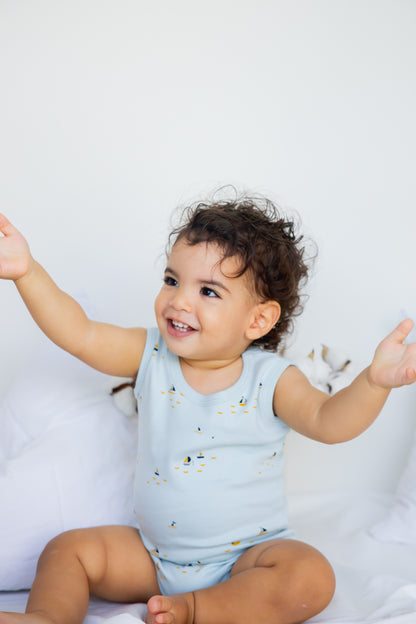 Toddler standing with arms raised in a sky blue sleeveless bodysuit