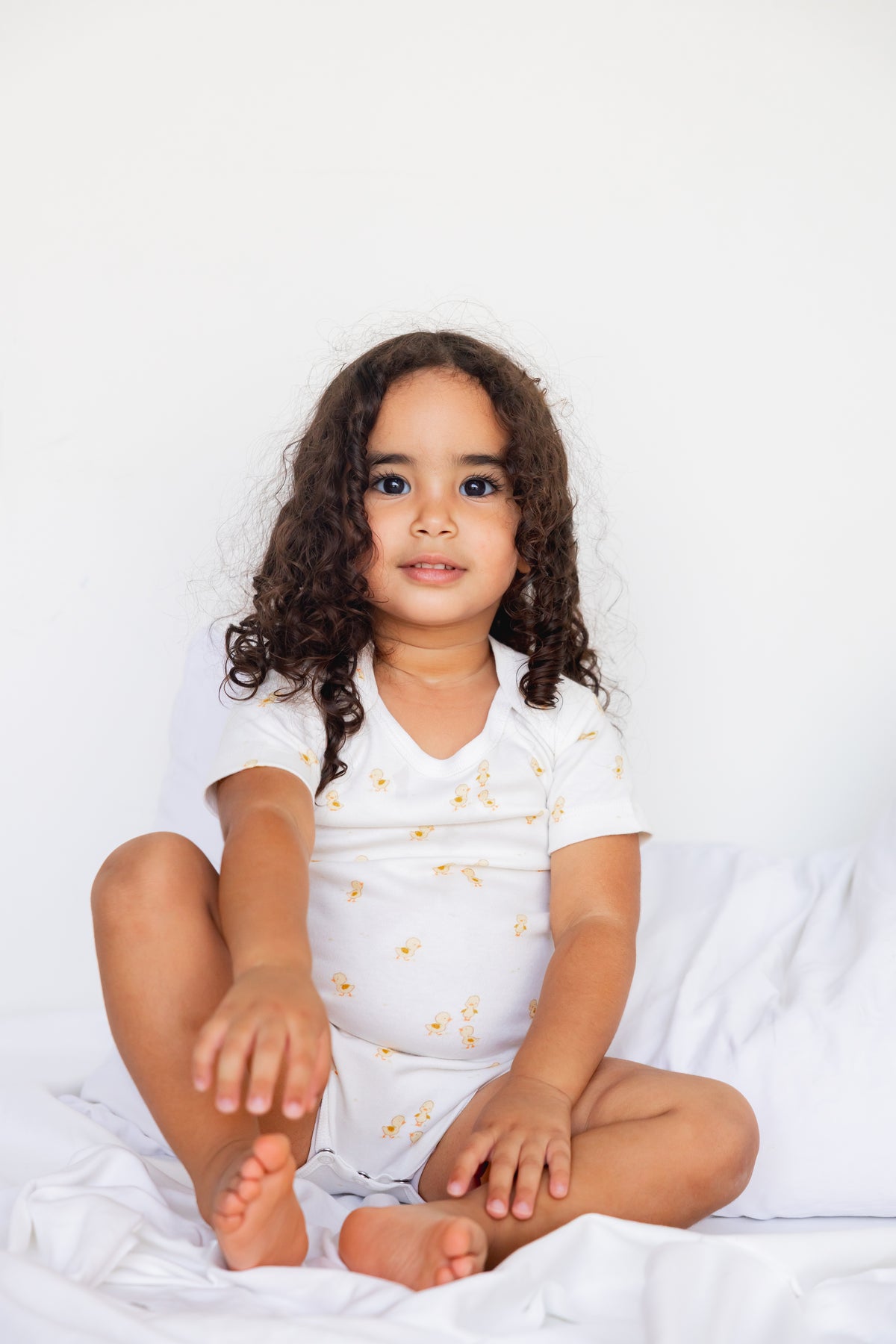 Toddler sitting in a white Ducky Days print short sleeve bodysuit