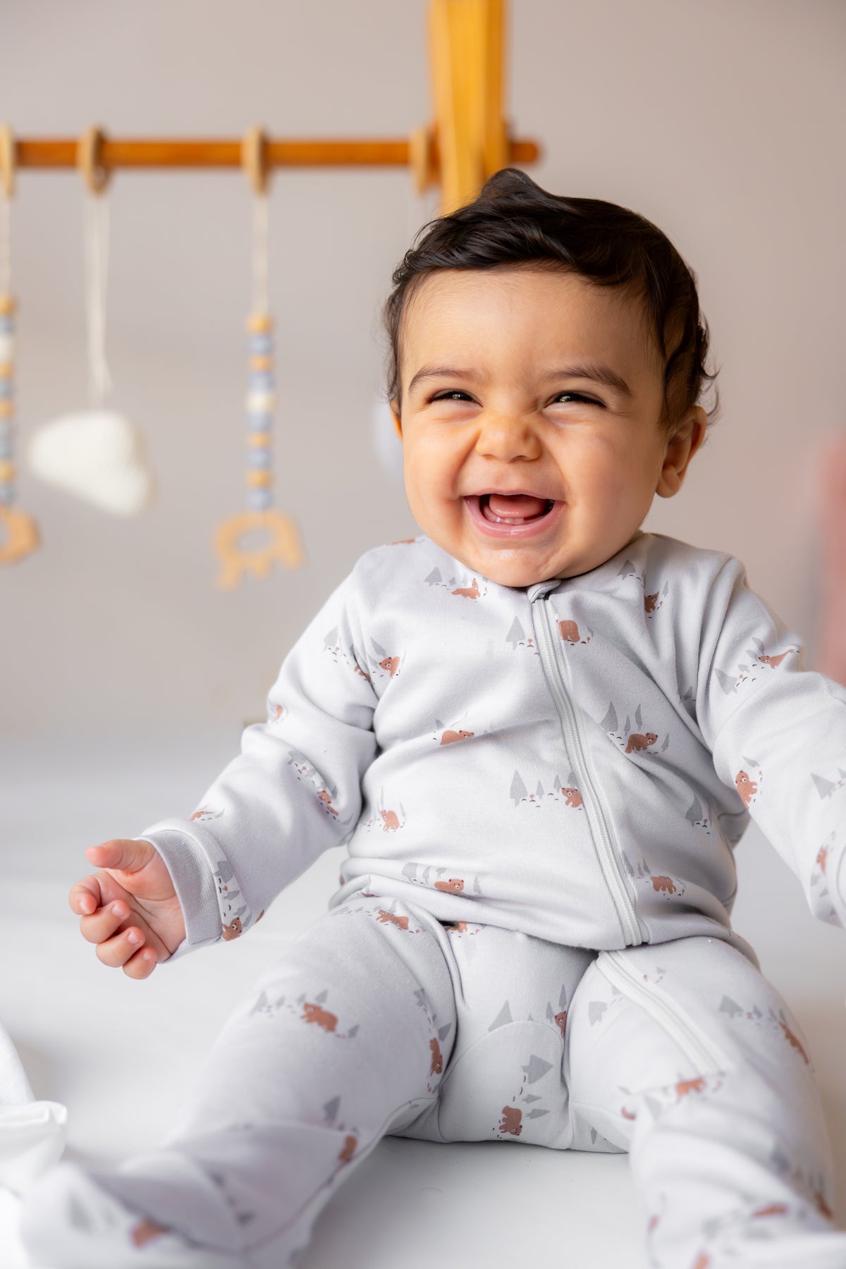 Smiling baby standing in the Woodland Bear footed zipper sleepsuit