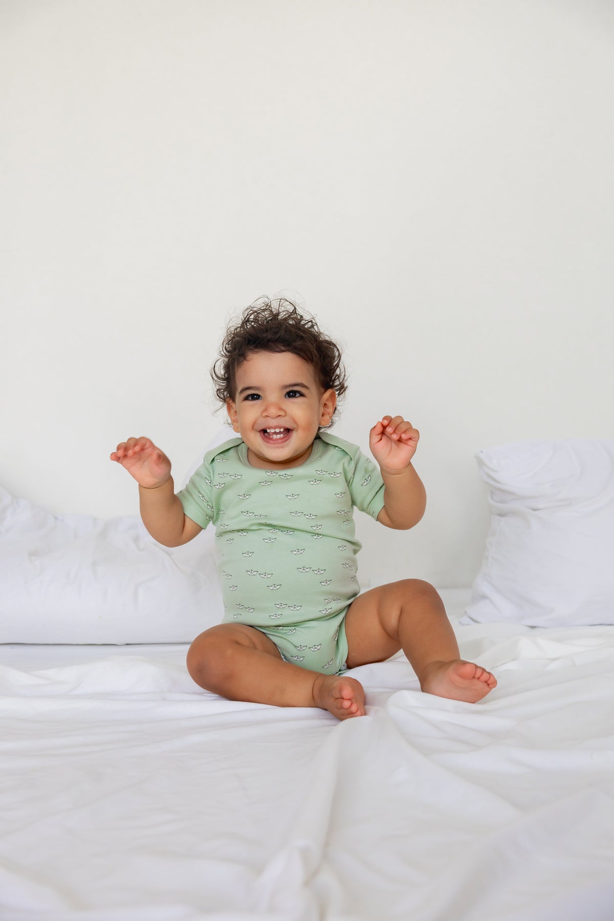 Baby sitting in a sage short sleeve bodysuit from the Boats three-pack