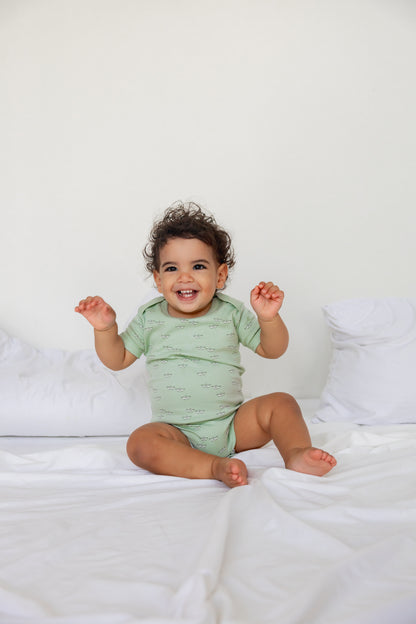 Baby sitting in a sage short sleeve bodysuit from the Boats three-pack
