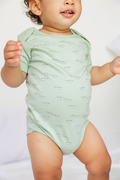 Baby standing in a sage short sleeve bodysuit