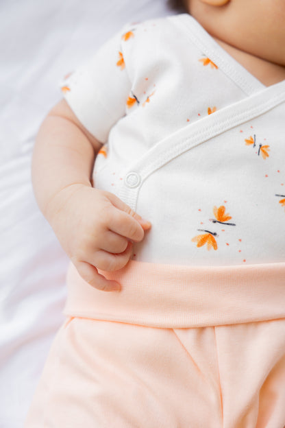 Close-up of the Dainty Wings kimono bodysuit and coral shorts