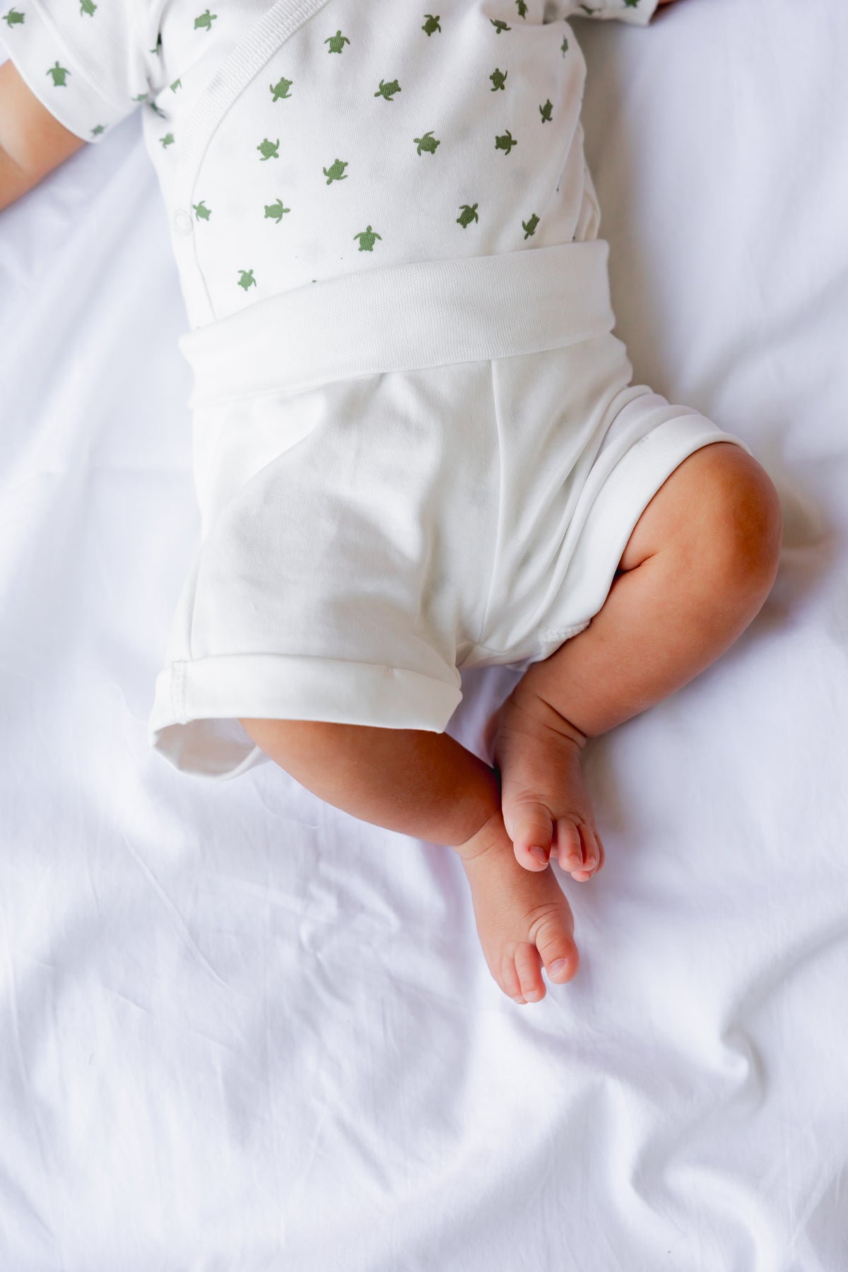 Baby lying down wearing the Sea Shells print shorts