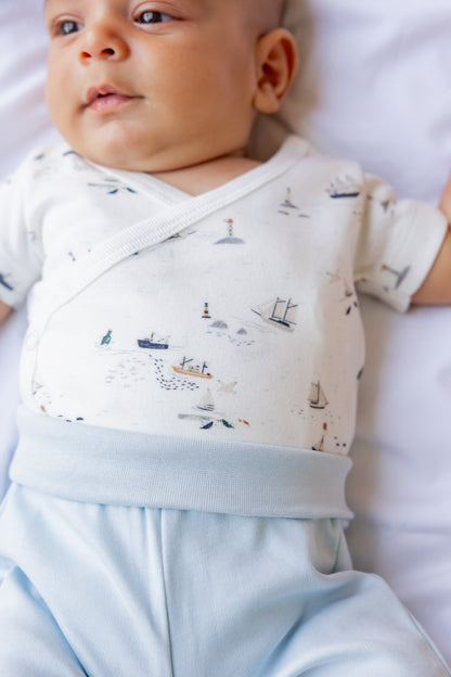 Baby lying down in a printed short sleeve top and matching pale blue shorts