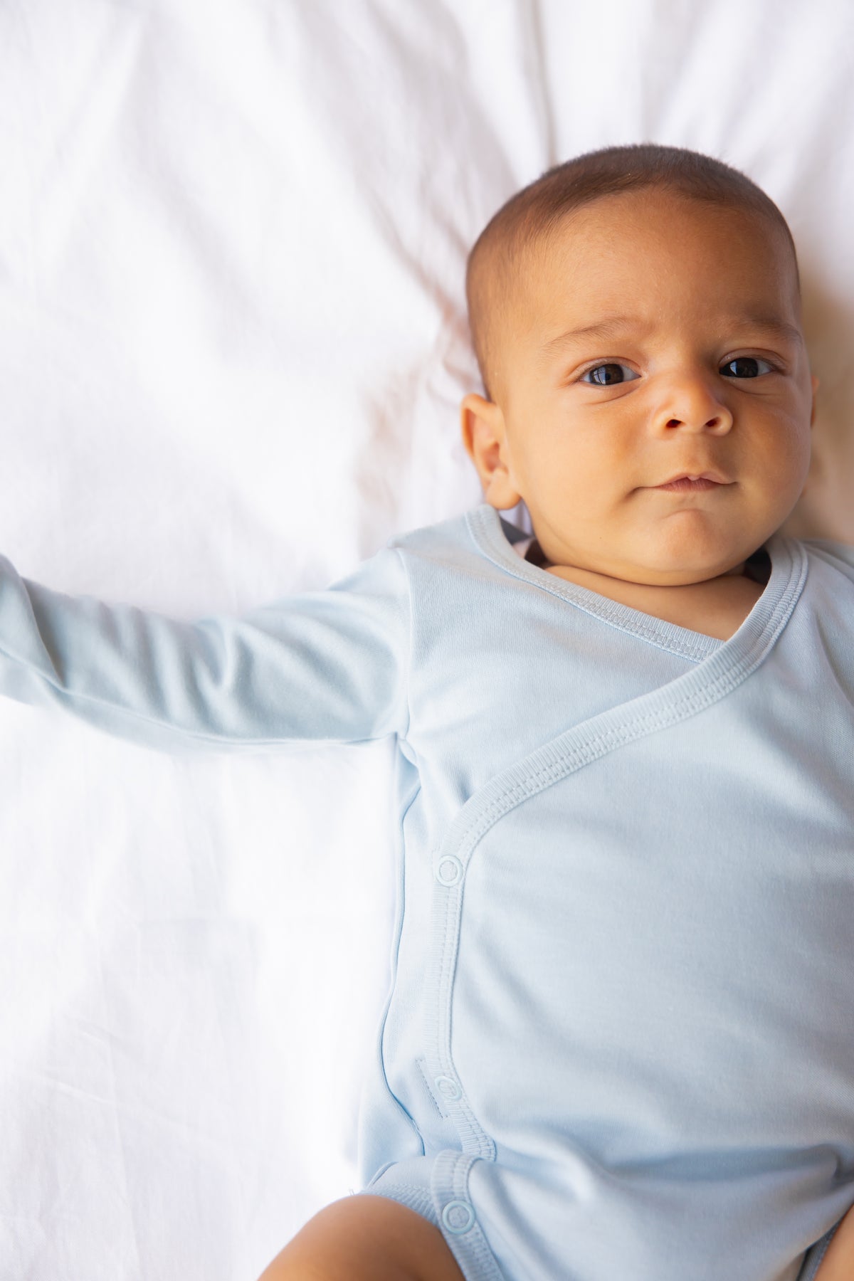 Baby lying down in a sky blue long sleeve kimono bodysuit