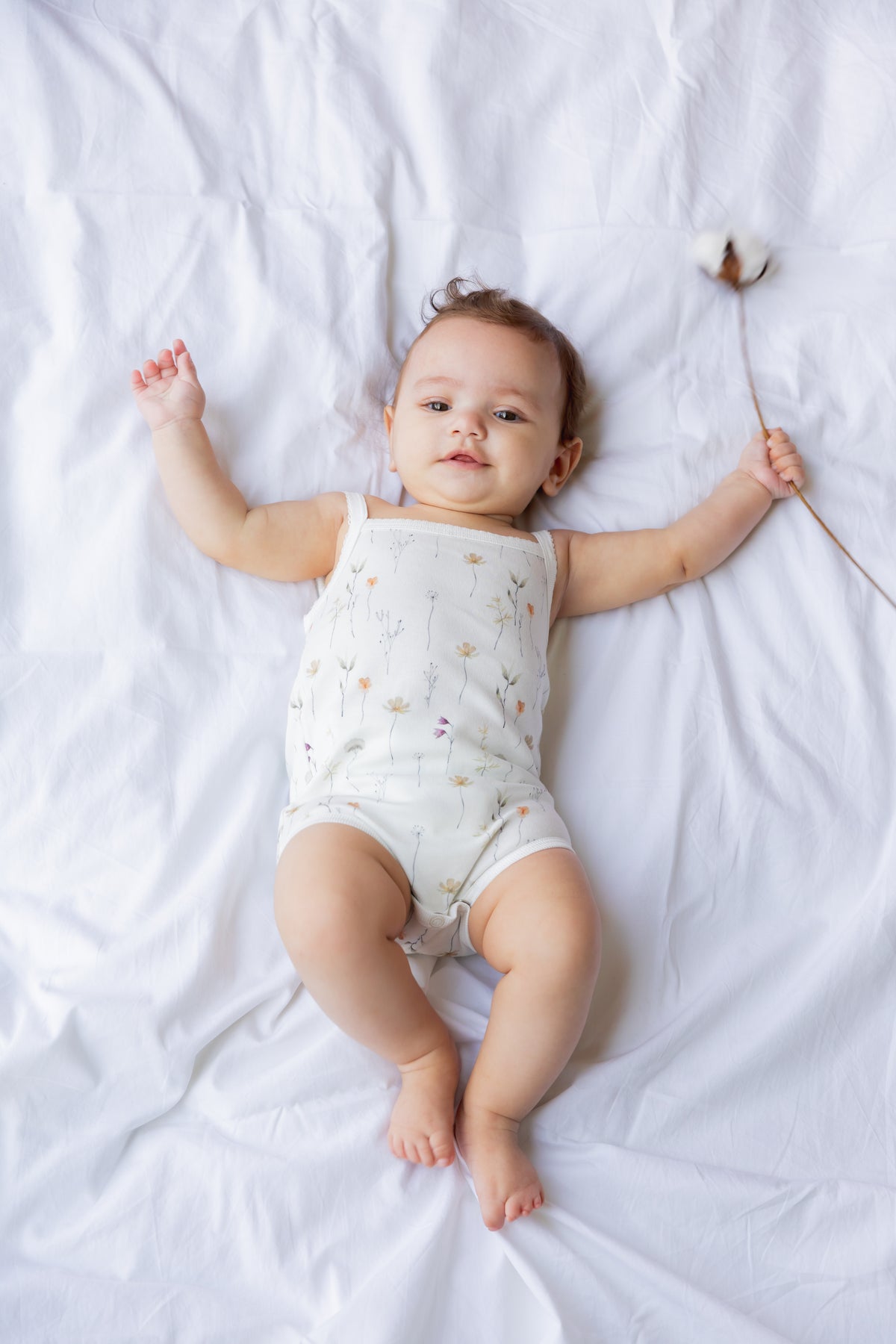 Baby lying down with arms raised in the Wild Flowers sleeveless bodysuit