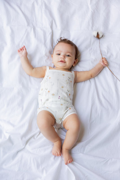Baby lying down with arms raised in the Wild Flowers sleeveless bodysuit