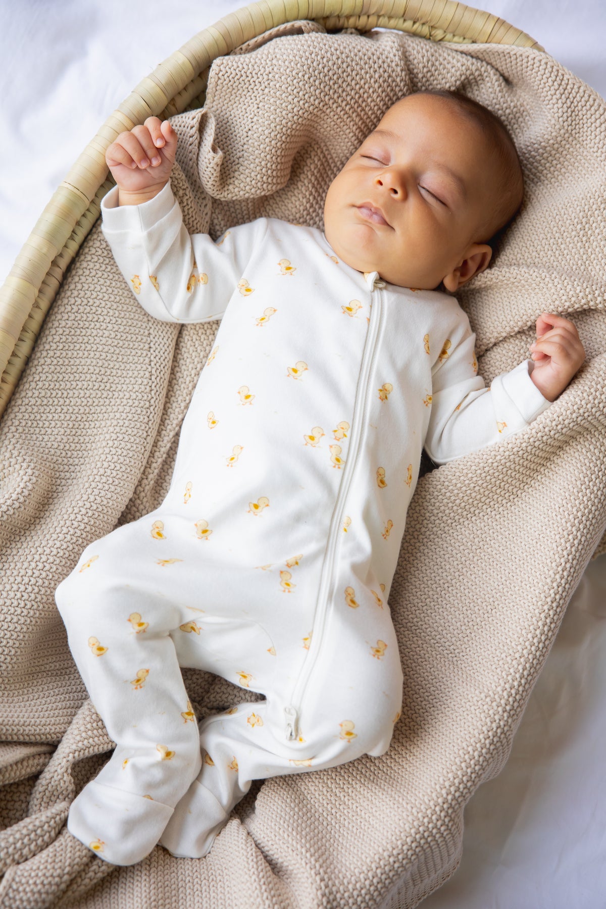Newborn asleep in the Ducky Days print two-way zipper sleepsuit