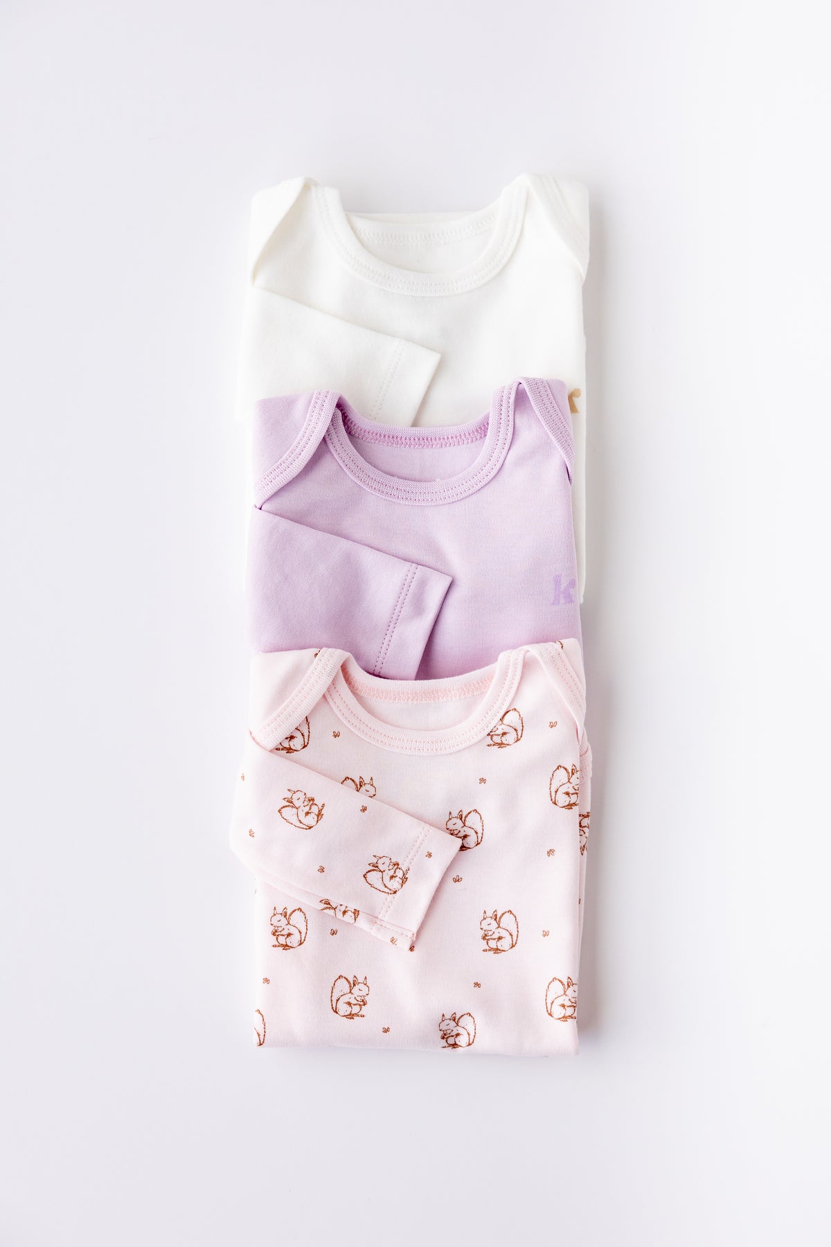 Three long sleeve bodysuits in lavender, white and Soft Pastel print