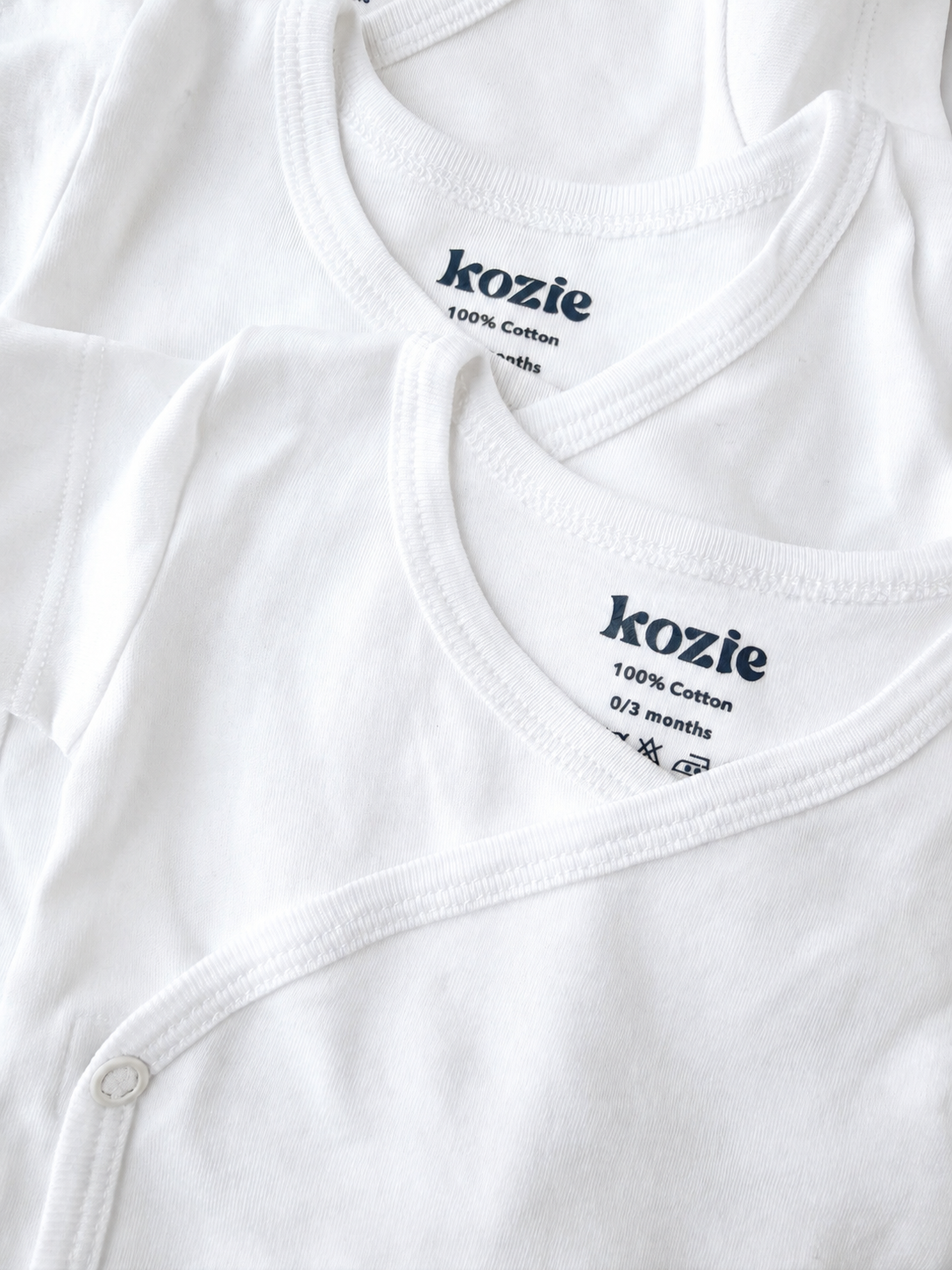 Close-up of the wrap neckline and Kozie label on a white kimono bodysuit