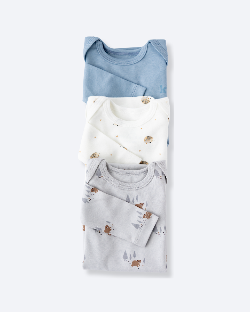 Three long sleeve bodysuits in dusty blue, white and Woodland print
