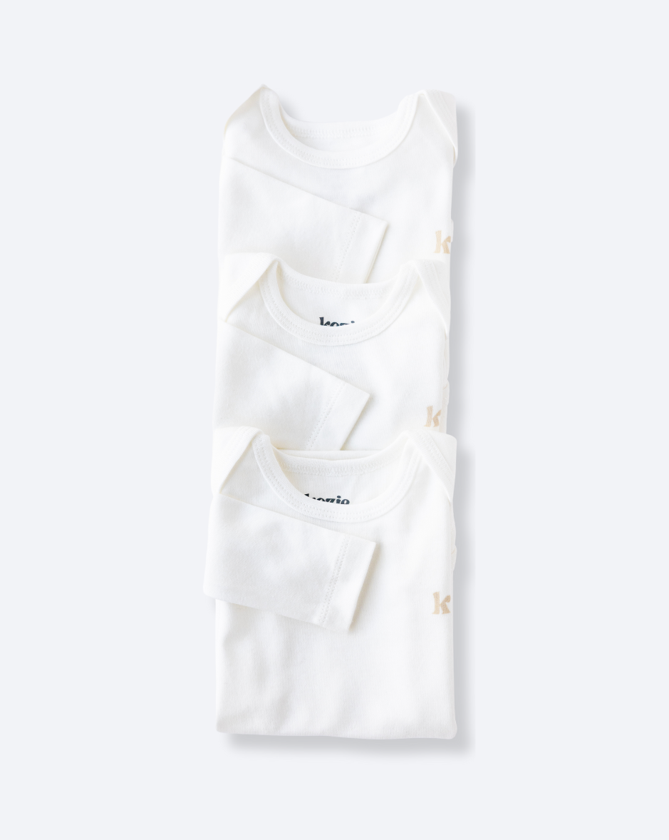 Three white long sleeve bodysuits folded and stacked