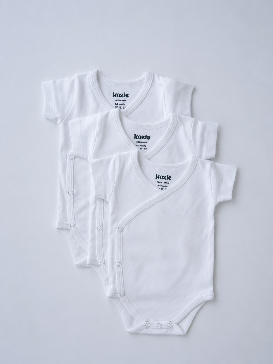 Three white short sleeve kimono bodysuits, laid flat
