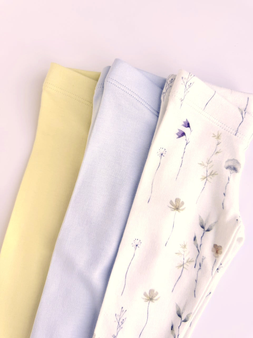 Wildflower print leggings laid out with a plain lavender pair