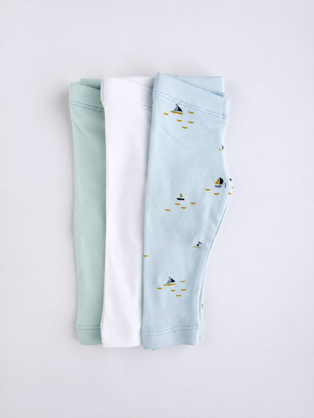 Three pairs of baby leggings in sage, white and Blue Sails print