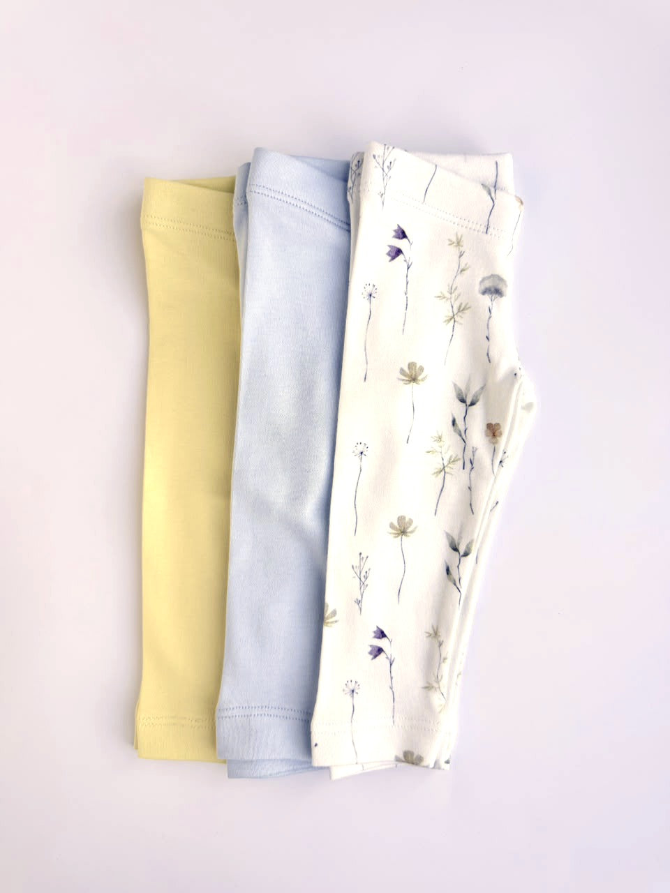Three pairs of baby leggings in butter yellow, white and Wildflower print