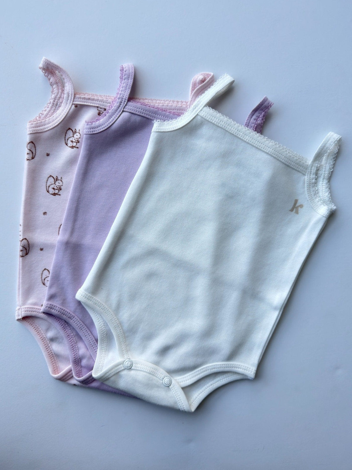 Sleeveless bodysuits in lavender and pale blue, laid flat